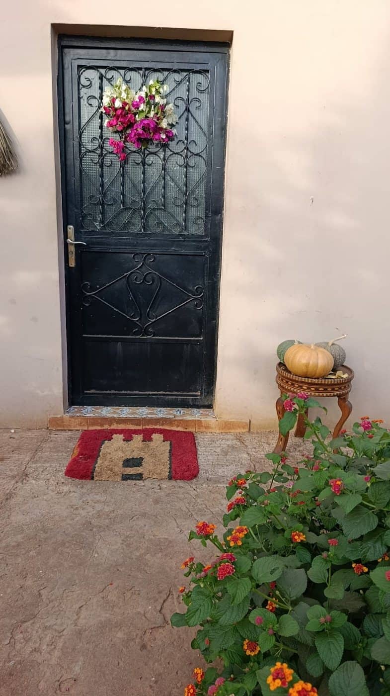 La porte d’entrée fleurie, avec les courges de la ferme posées à côté