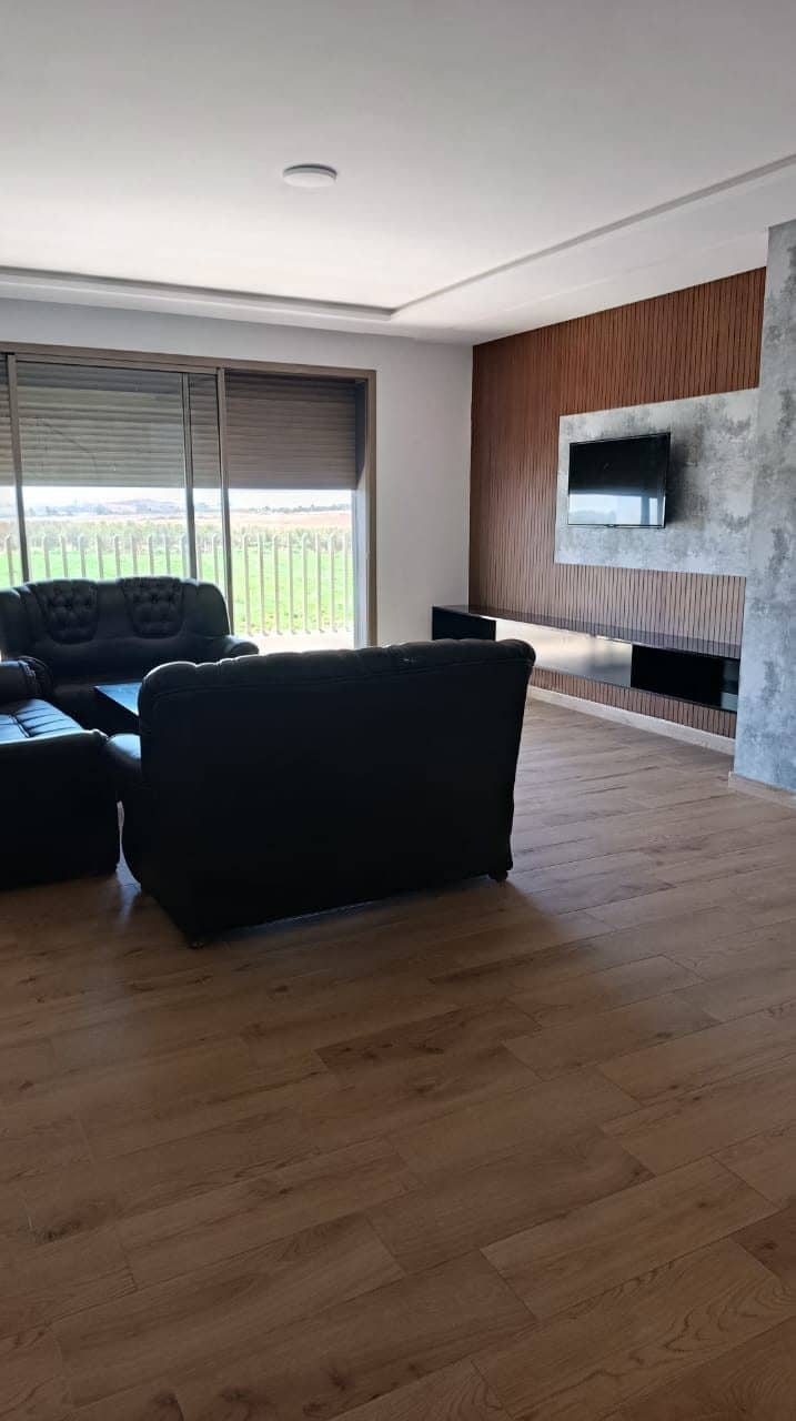 Le salon avec ses canapés et sa baie sur la campagne